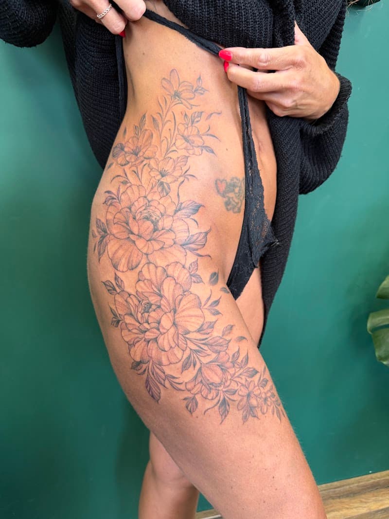Grote fineline bloemen tattoo op heup en bovenbeen.