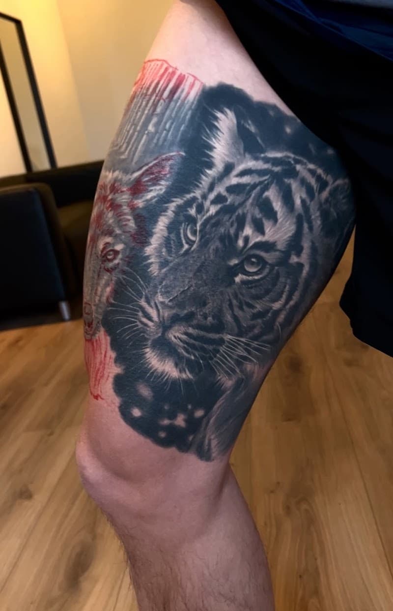 Realistische tijgerkop in zwart-wit met rode omlijning van een wolf op het bovenbeen.