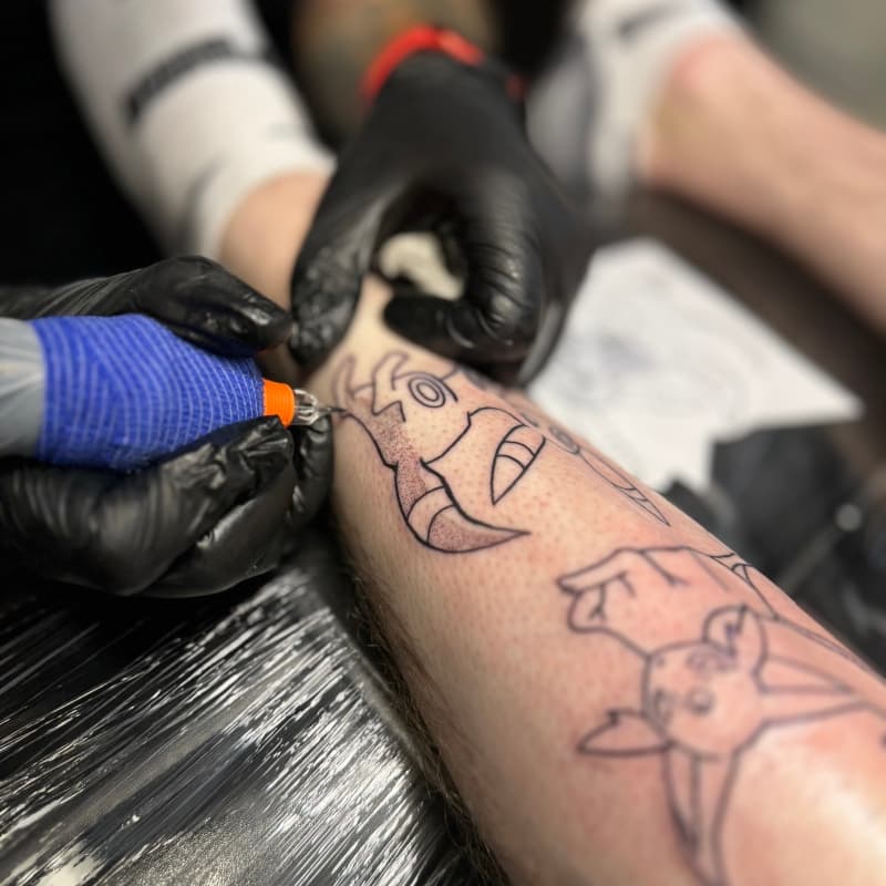 Line art Pokémon tattoo in wording op onderbeen.