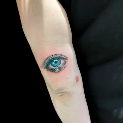 Realistisch blauw oog met een traan op de achterkant van de bovenarm.