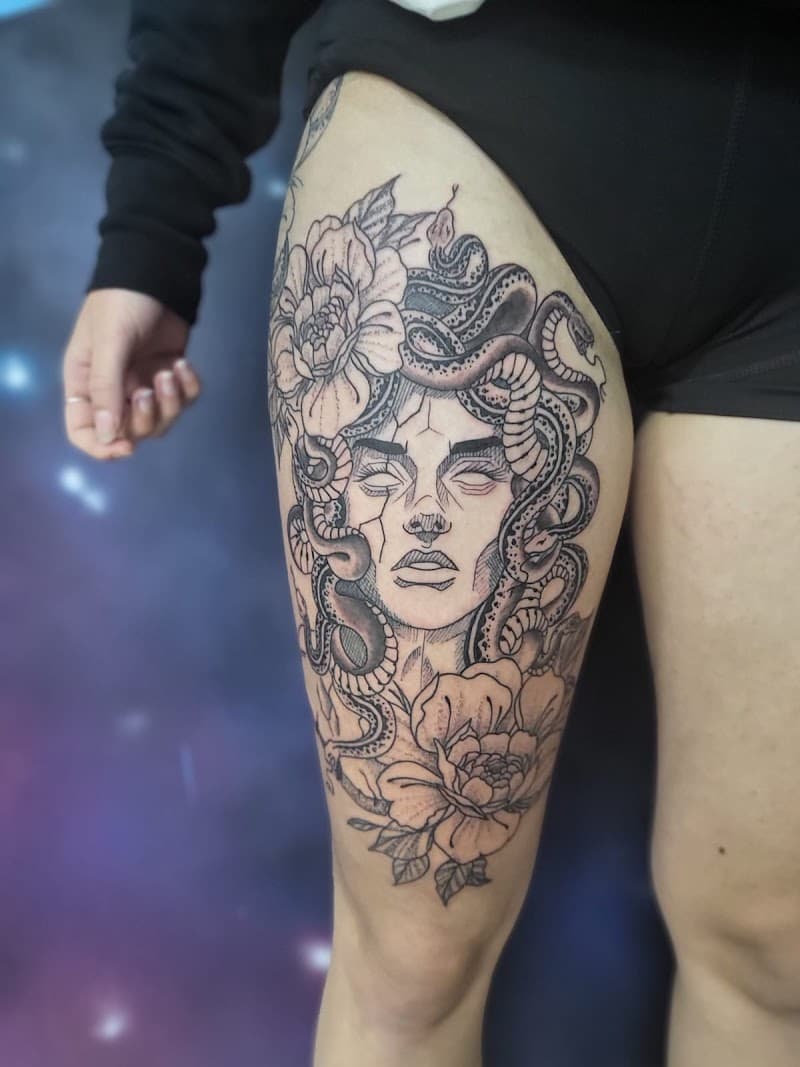 Grote Medusa tattoo met slangen en bloemen op bovenbeen.
