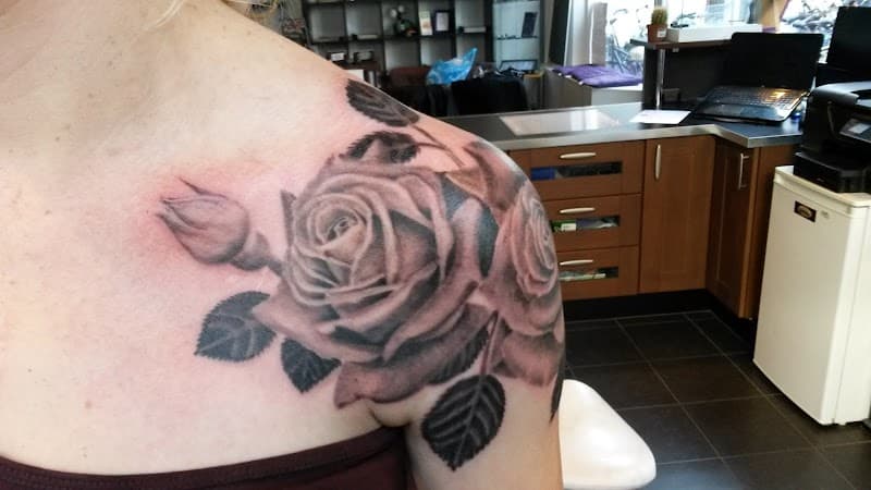 Grote zwart-wit realistische rozen tattoo op schouder en borst.