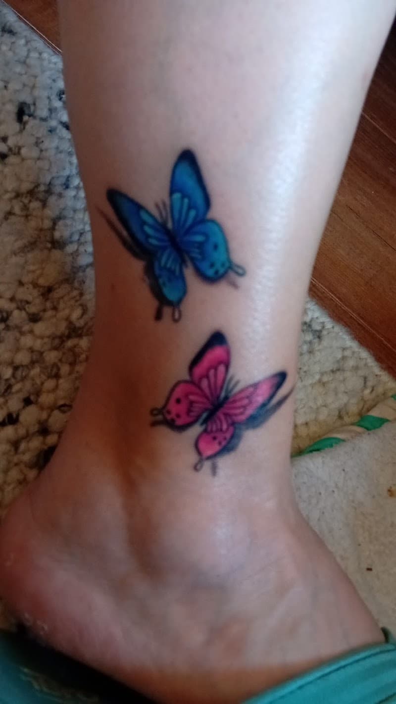 Twee vlinders, één blauw en één roze, op de enkel.