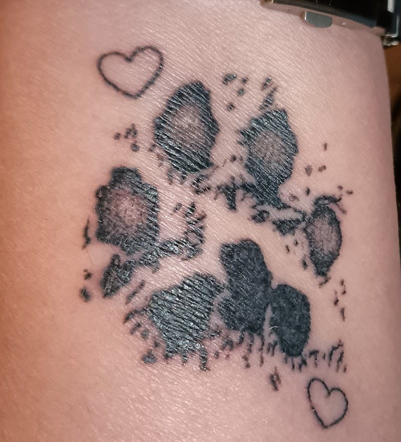 Zwart-witte hondenpoot afdruk met twee kleine hartjes.