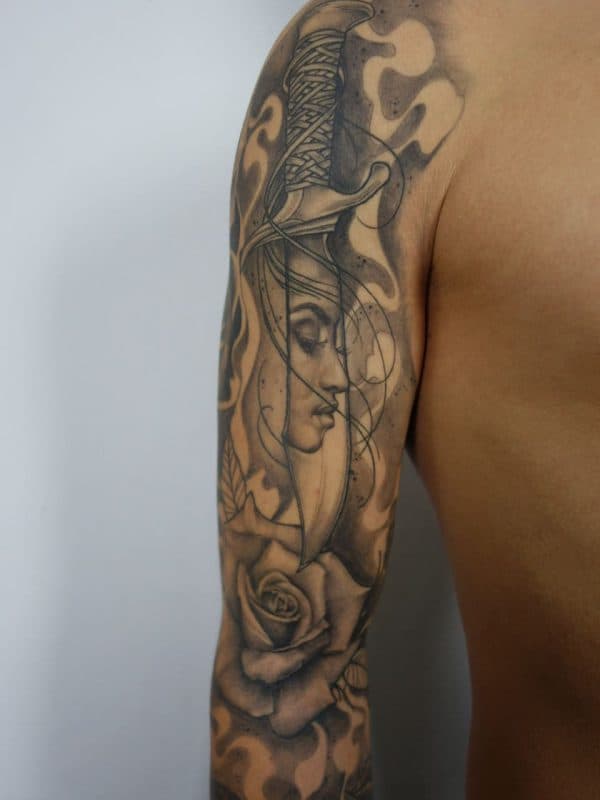 Realistische dolk met vrouwenportret en roos op bovenarm.