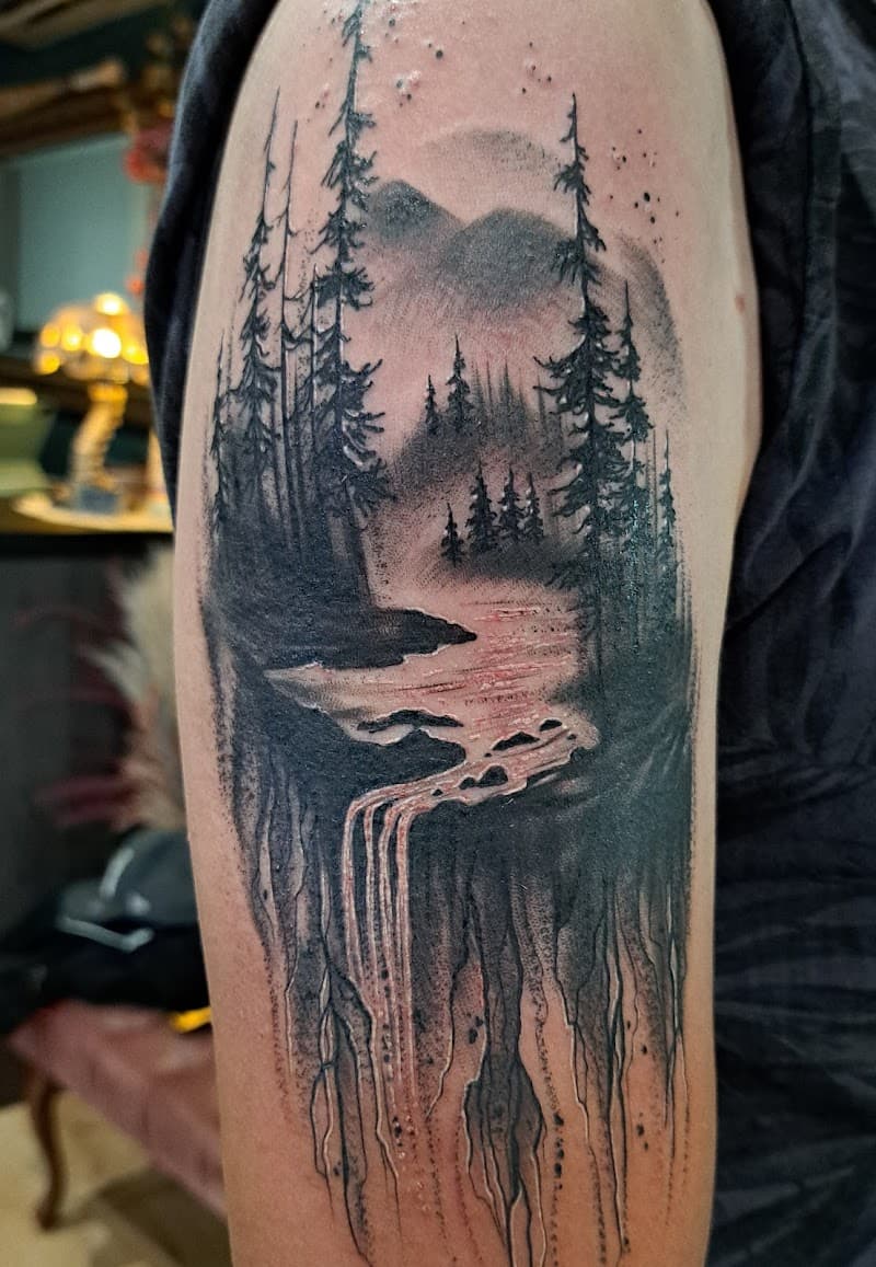Zwart-wit landschap tattoo met bos, bergen en waterval op bovenarm.