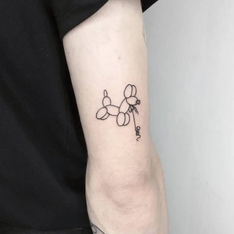 Fineline tattoo van een ballonhondje op de achterkant van de bovenarm.