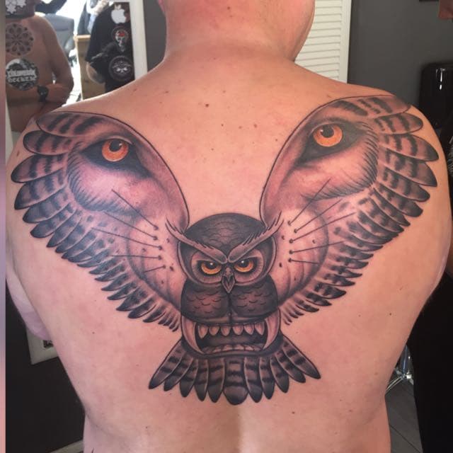 Grote uil met gespreide vleugels en felle oranje ogen op de bovenrug.