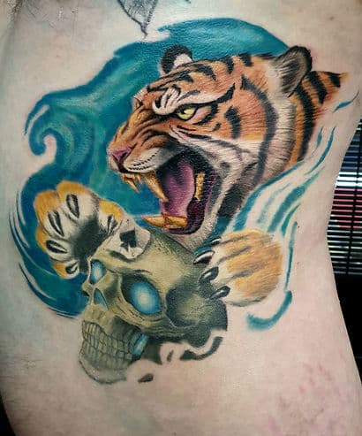 Kleurrijke tattoo van een brullende tijger en een schedel met blauwe gloed.