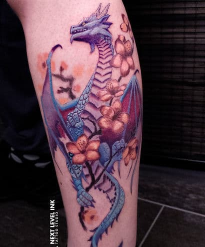 Blauwe en paarse draak met oranje bloemen op onderbeen.