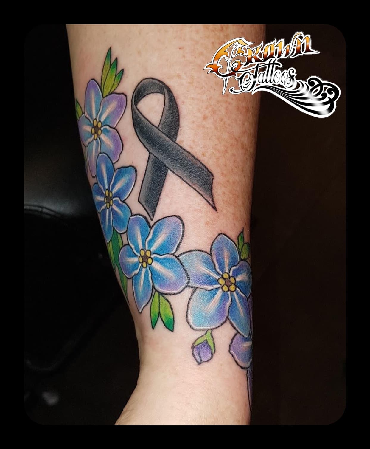 Zwart lint met blauwe vergeet-mij-nietjes op onderarm.