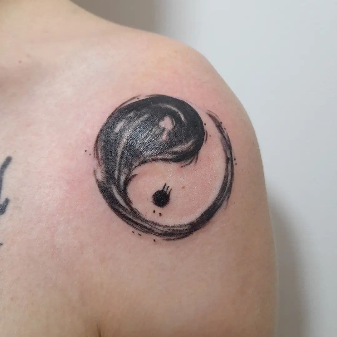 Yin Yang tattoo in penseelstreek stijl op de schouder.