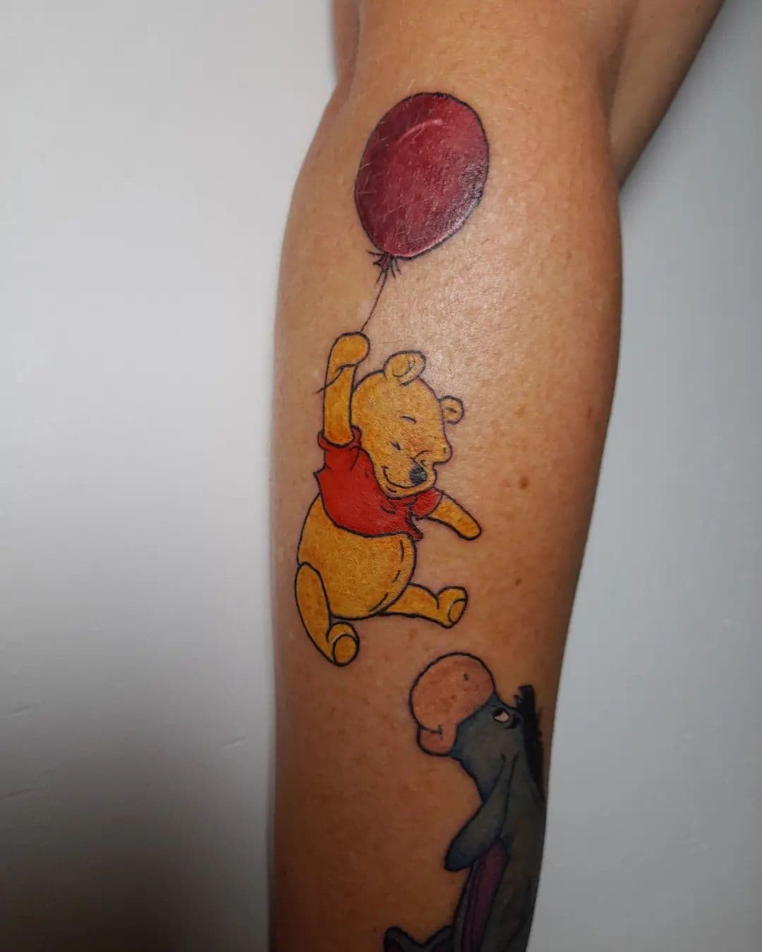 Winnie de Poeh met rode ballon en Iejoor op onderbeen.