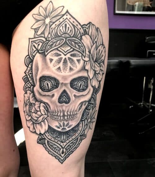 Zwart-wit schedel met mandala en bloemen op bovenbeen.