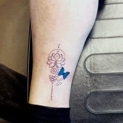 Fineline unalome met lotus en blauwe vlinder op enkel.