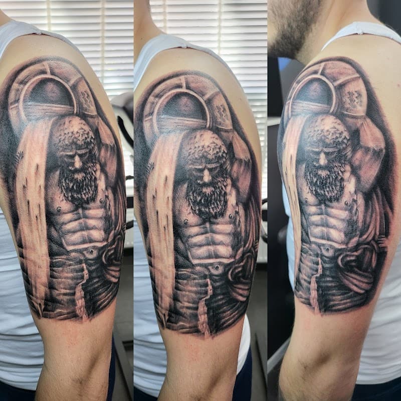 Realistische zwart-wit tattoo van Atlas die de wereld draagt op een bovenarm.