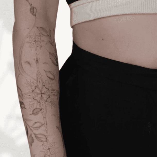 Fineline geometrische en florale tattoo op de onderarm.