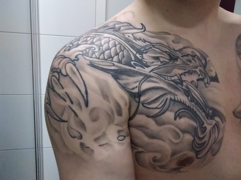 Zwart-wit Japanse draak tattoo op schouder en borst.