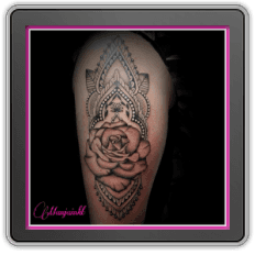 Zwart-wit tattoo van een roos in een ornamenteel mandala patroon op de bovenarm.