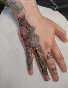 Biomechanische tattoo op vingers en hand, met kleine symbolen op ringvinger.