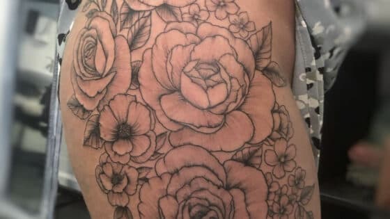 Grote fineline bloemen tattoo op bovenbeen.