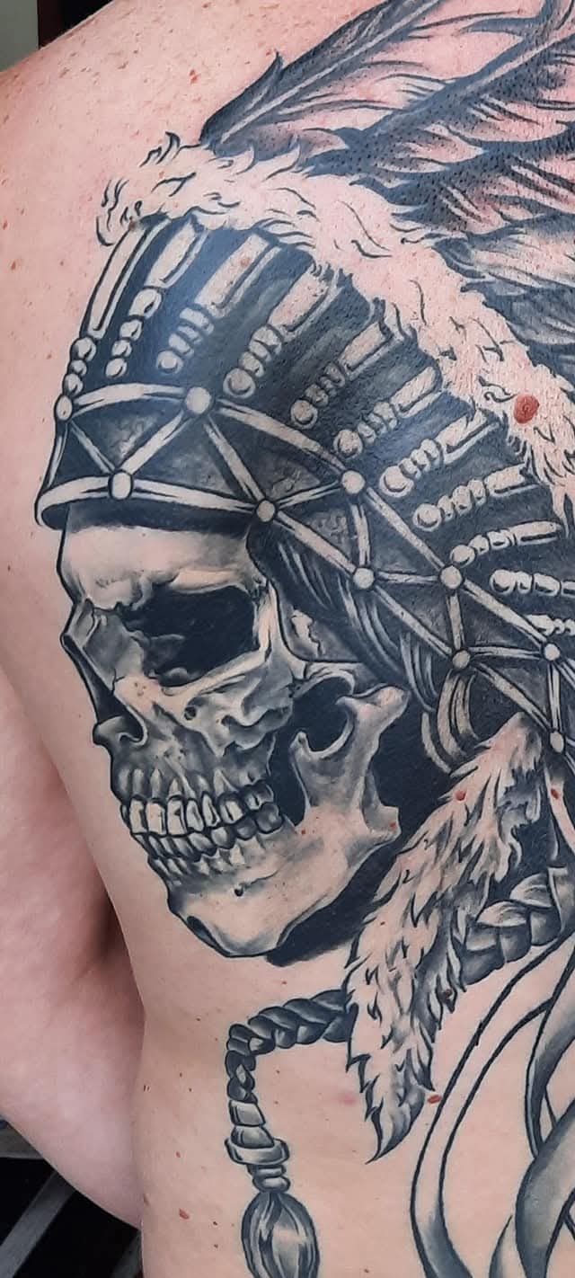 Realistische schedel met indianentooi op schouderblad.