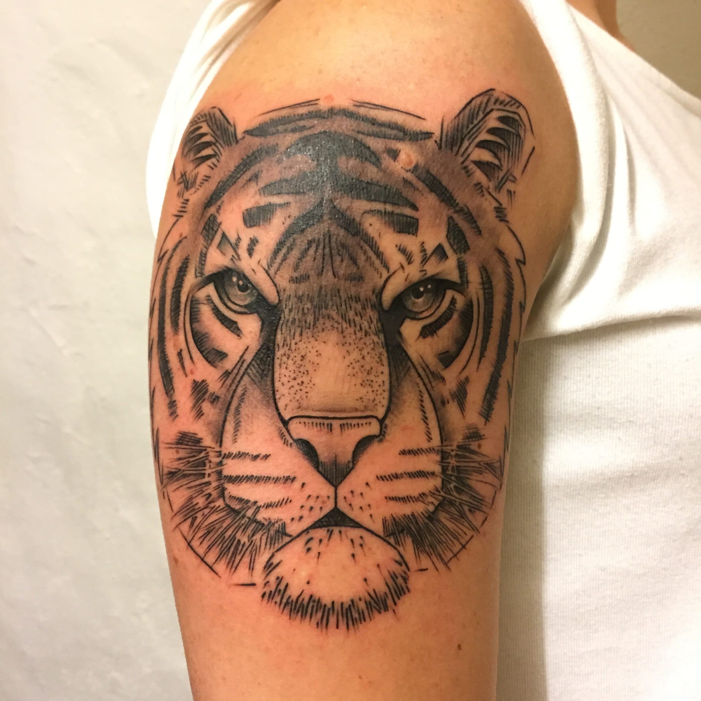 Close-up van een tijgerkop tattoo op de bovenarm.