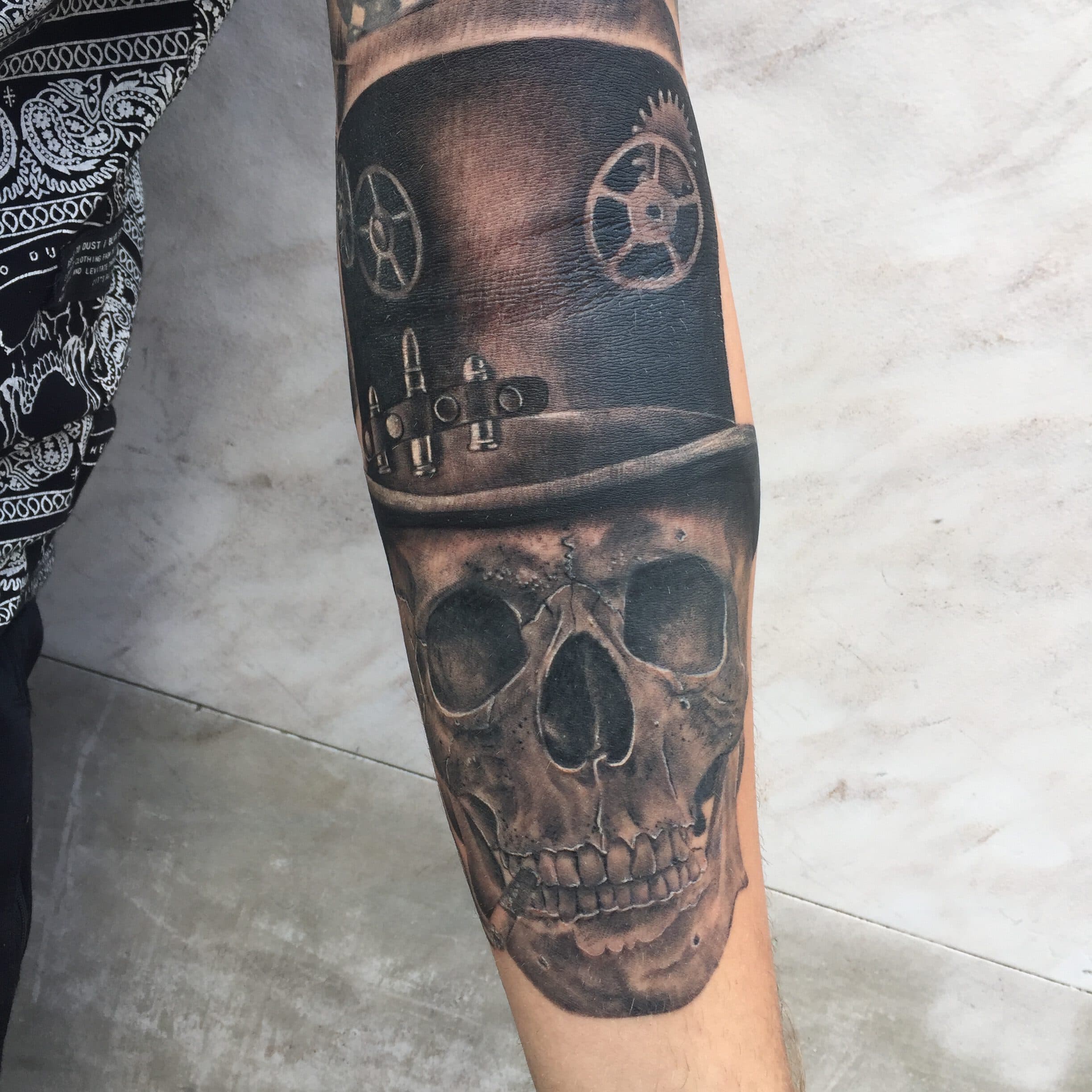 Realistische schedel met steampunk hoed en sigaar op onderarm.