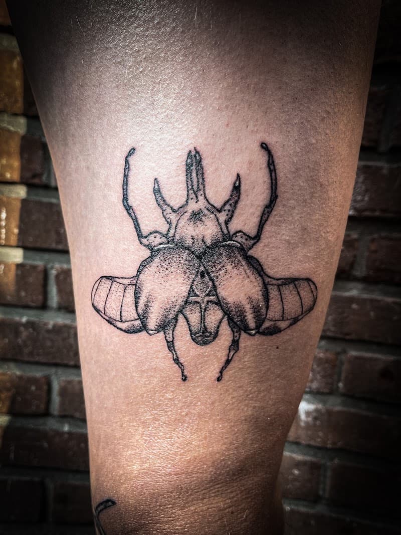 Gedetailleerde blackwork kever tattoo op het bovenbeen.