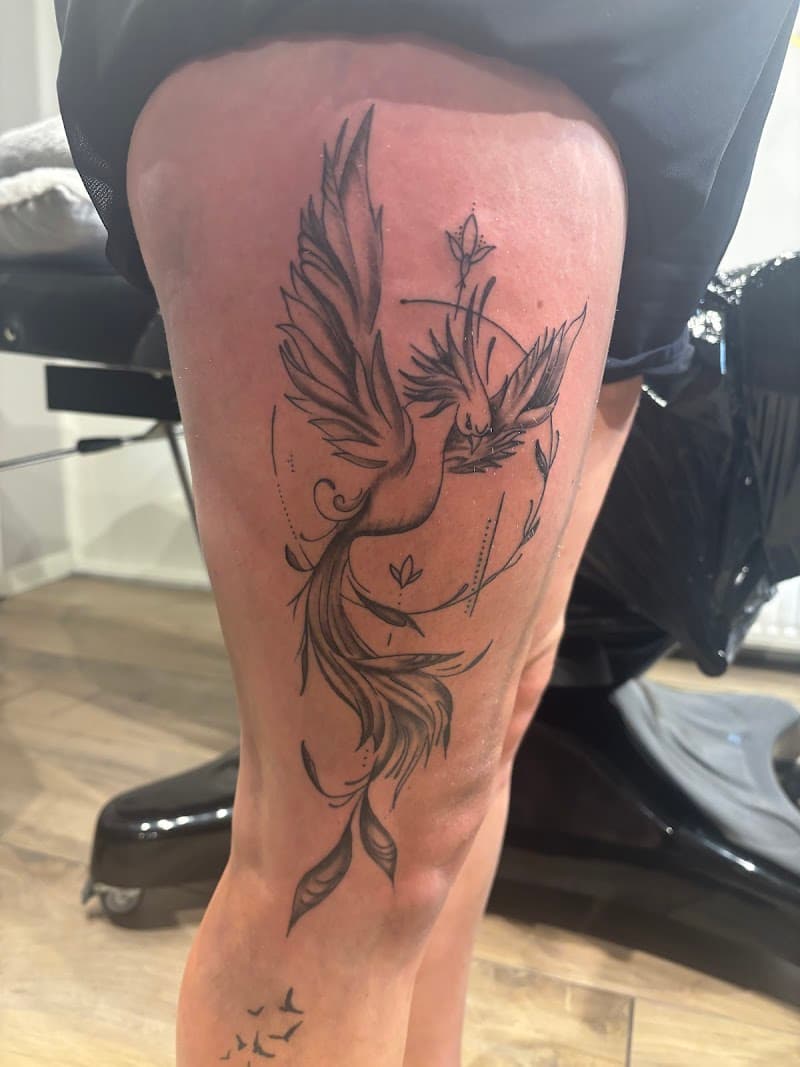 Fineline feniks met geometrische elementen op bovenbeen.