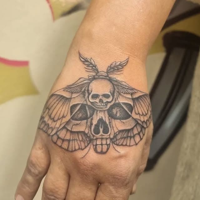 Zwart-wit doodshoofdvlinder tattoo op de hand.