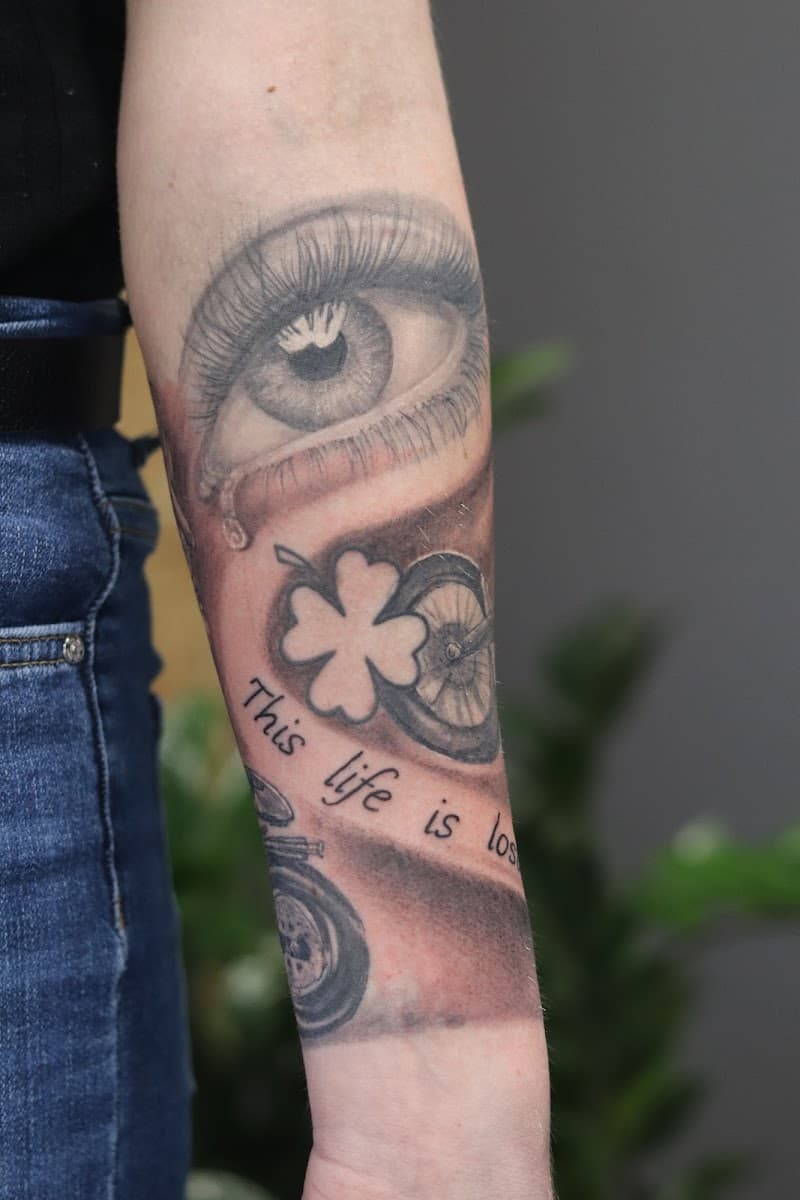 Realistisch oog, klavertje vier, fietswiel en tekst 'This life is los' op onderarm.