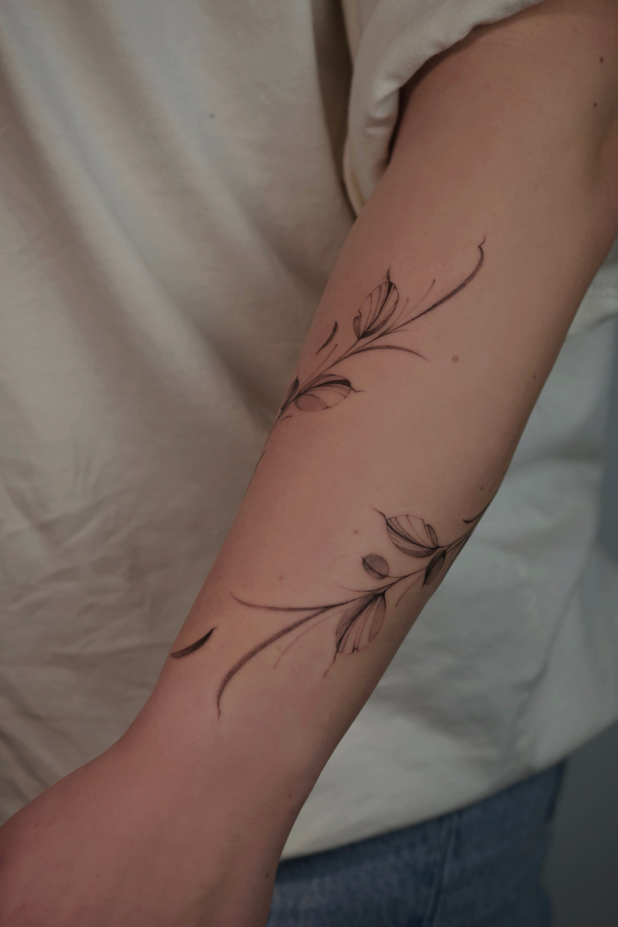 Fineline bladeren en takken op de onderarm.