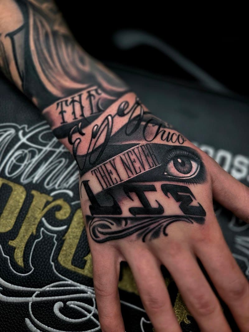 Zwart-wit handtattoo met tekst "THE EYES CHICO THEY NEVER LIE" en een oog.