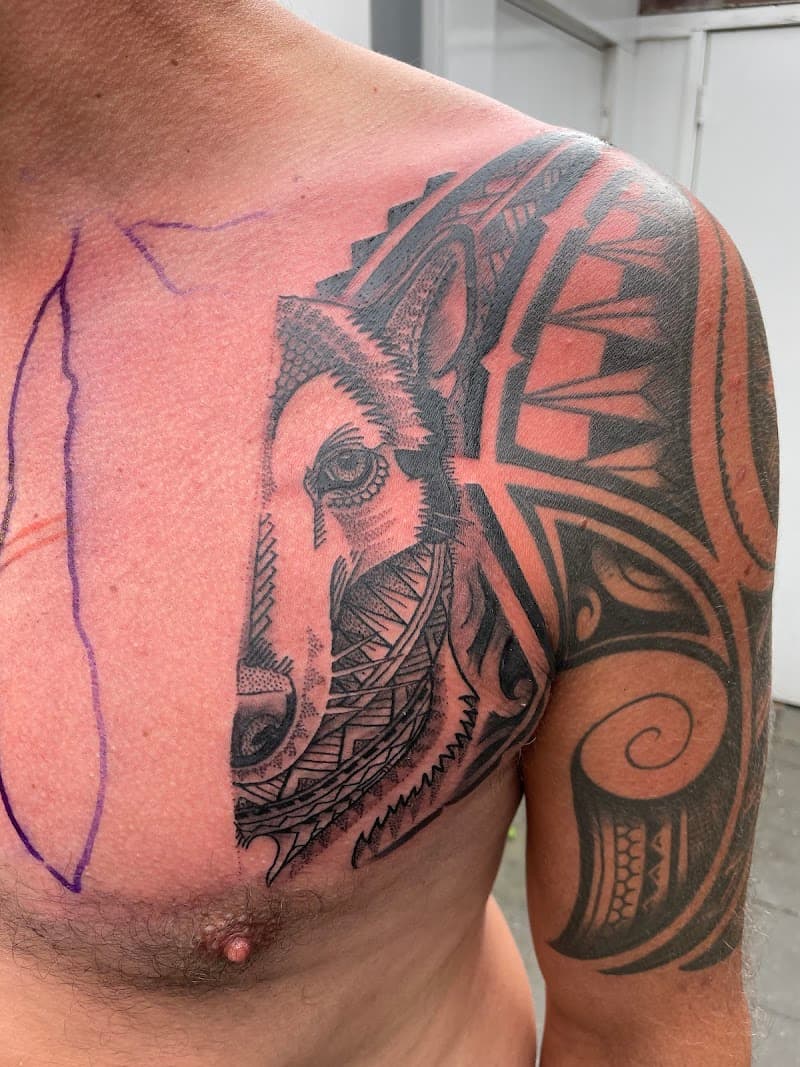 Grote blackwork wolfskop met geometrische patronen op borst en schouder.