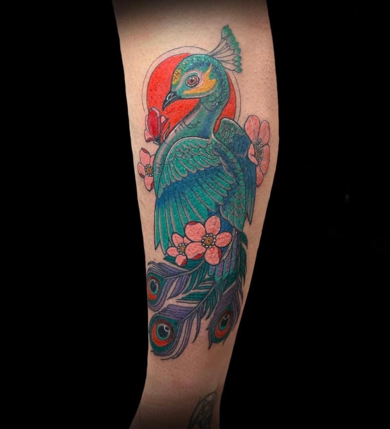 Kleurrijke pauw met bloemen en rode zon op onderbeen.