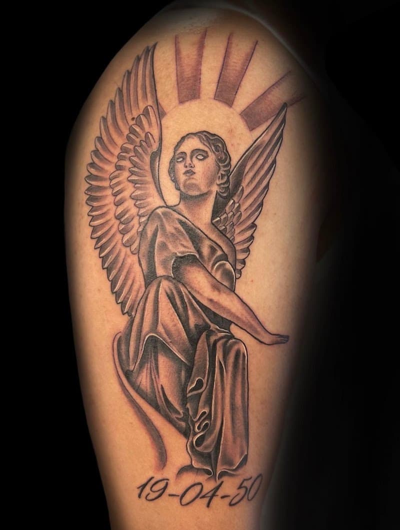 Black & grey tattoo van een engel met vleugels en de datum 19-04-50 eronder.