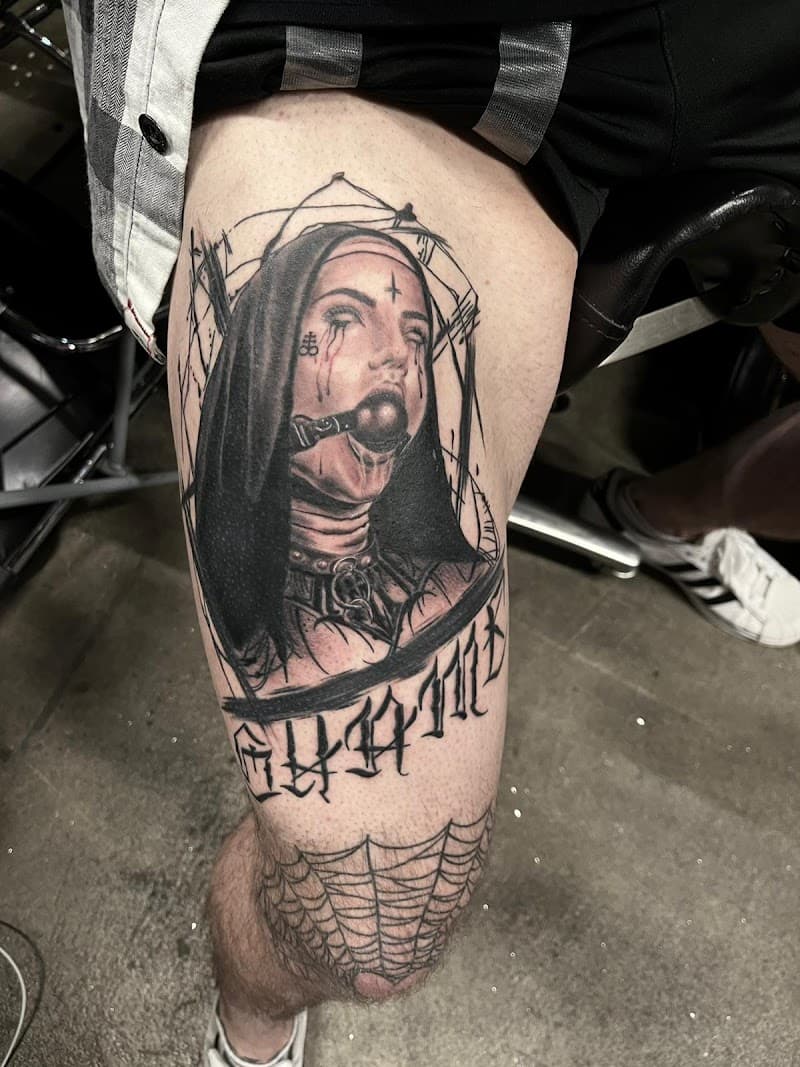Zwart-wit tattoo van een non met een bal gag en gotische tekst op het bovenbeen.