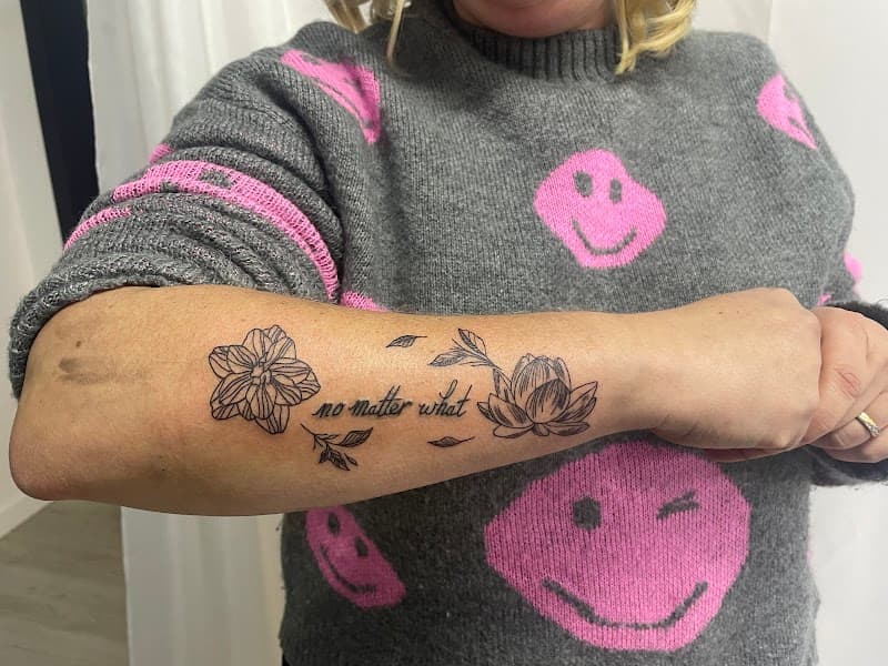 Fineline bloemen en tekst "no matter what" op onderarm.