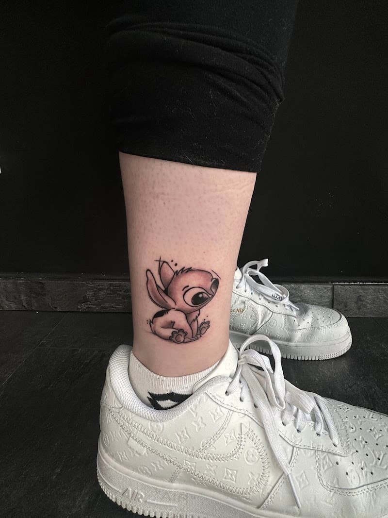 Kleine, schattige Stitch tattoo in blackwork stijl op de enkel.
