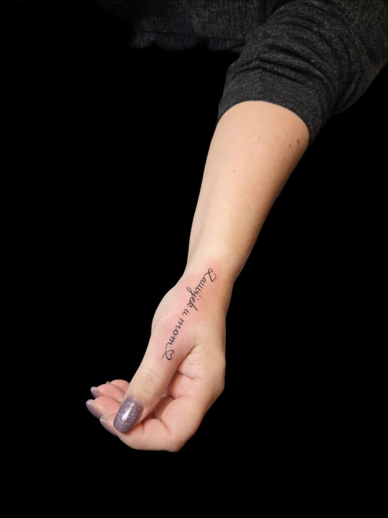 Fineline tekst 'Lauwyck u mom' met hartje op de zijkant van de hand.