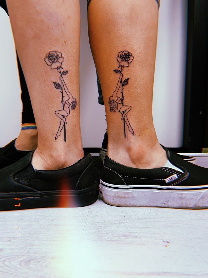 Fineline tattoo van vrouw hangend aan roos op beide enkels.