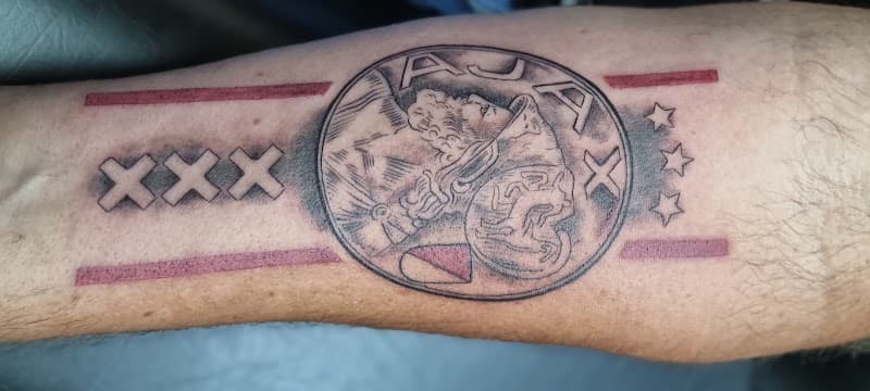 Ajax logo met drie kruizen en rode banen op onderarm.