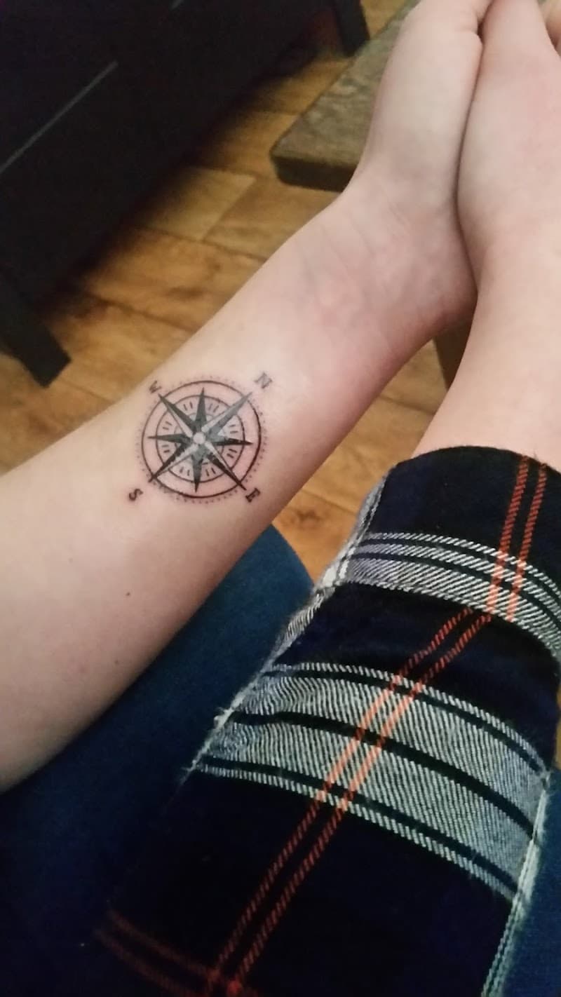 Kleine, minimalistische kompasroos tattoo op de binnenkant van de onderarm.