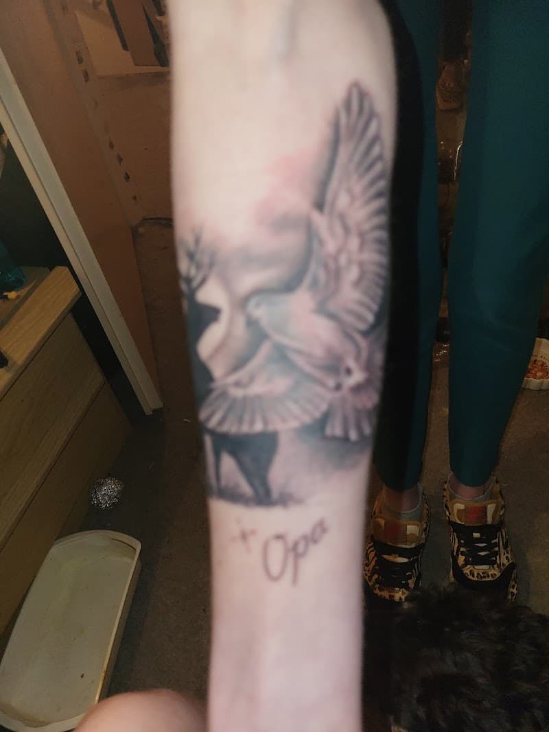 Zwart-wit tattoo van een duif die overgaat in een gezicht, met 'Opa' eronder.