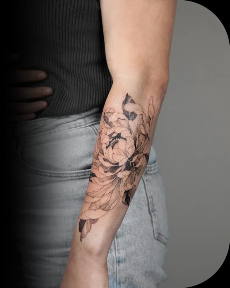 Grote, gedetailleerde pioenroos tattoo op de onderarm in zwart-wit.