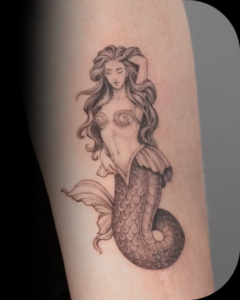 Fineline zeemeermin tattoo op de bovenarm.