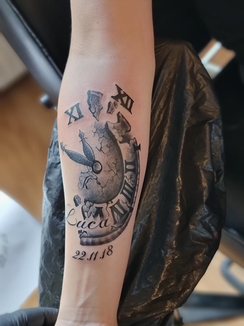 Gebroken klok met Romeinse cijfers, naam 'Luca' en datum '22.11.18' op onderarm.
