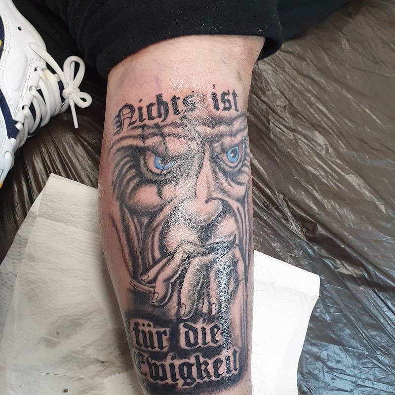 Blackwork tattoo van een oud, rokend gezicht met blauwe ogen en Duitse tekst.
