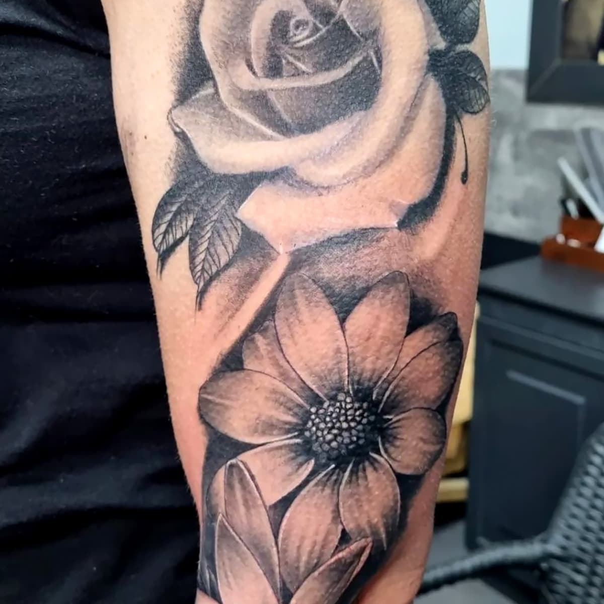 Zwart-wit realistische roos en madeliefje op bovenarm.